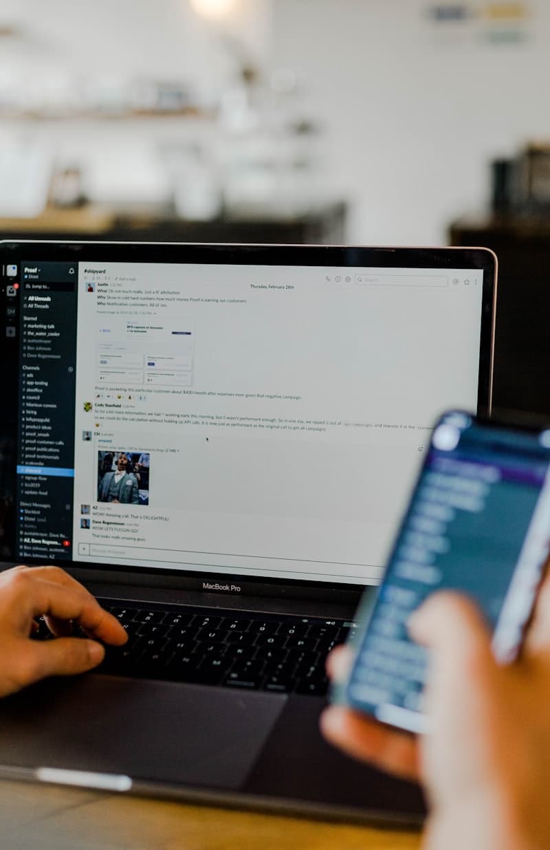 Working on a laptop with a banking app on the phone